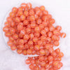 top view of a pile of 12mm Coral Orange Cats Eye Acrylic Bubblegum Beads - 20 Count