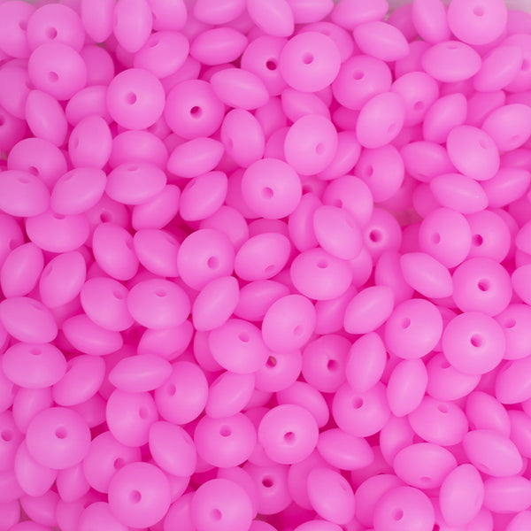 top view of a pile of 12mm Bright Pink Glow in The Dark Lentil Silicone Bead