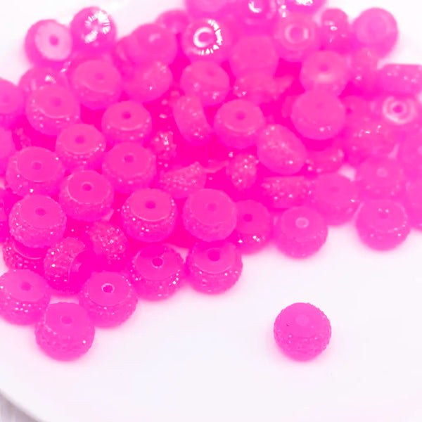 front view of a pile of 12mm Pink Glow In the Dark Resin Rondelle Spacer Beads - Set of 20