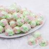 front view of a pile of 16mm Spearmint Green with Pink Flowers luxury acrylic beads