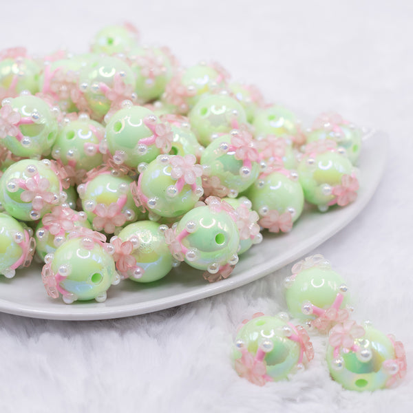 front view of a pile of 16mm Spearmint Green with Pink Flowers luxury acrylic beads
