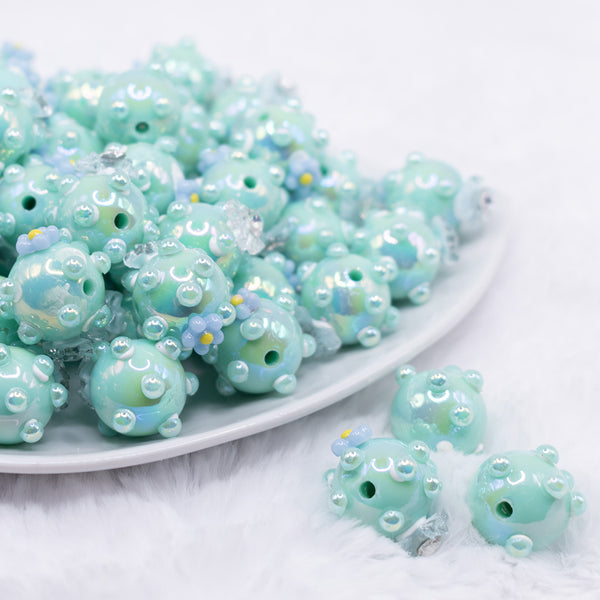 front view of a pile of 16mm Teal with Blue Flowers luxury acrylic beads