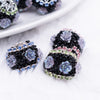 close up view of a pile of 20mm Black luxury acrylic beads with iridescent flower accents