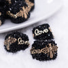 close up view of a pile of 20mm Black Square luxury bead with gold Bee and Love Accents