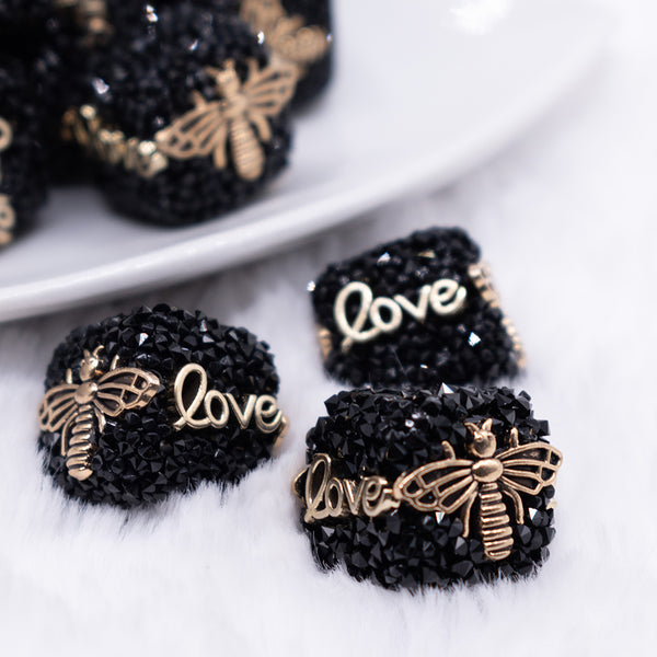 close up view of a pile of 20mm Black Square luxury bead with gold Bee and Love Accents
