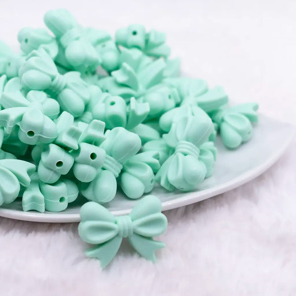 front view of a pile of 25mm Mint Green Bow Knot silicone bead