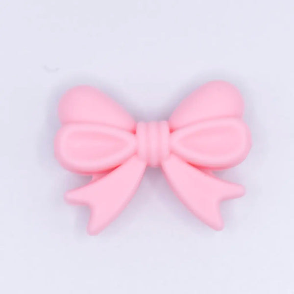 top view of a pile of 25mm Quartz Pink Bow Knot silicone bead