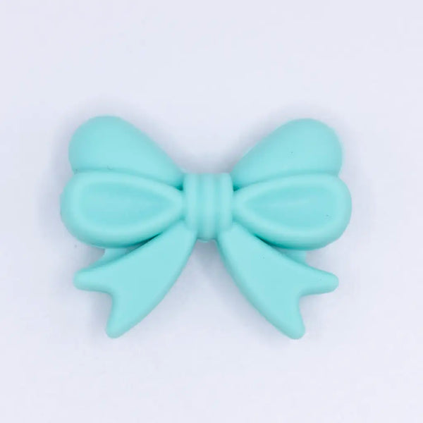 top view of a pile of 25mm Turquoise Bow Knot silicone bead