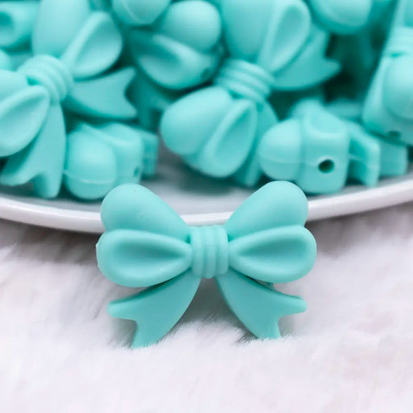 front view of a pile of 25mm Turquoise Bow Knot silicone bead