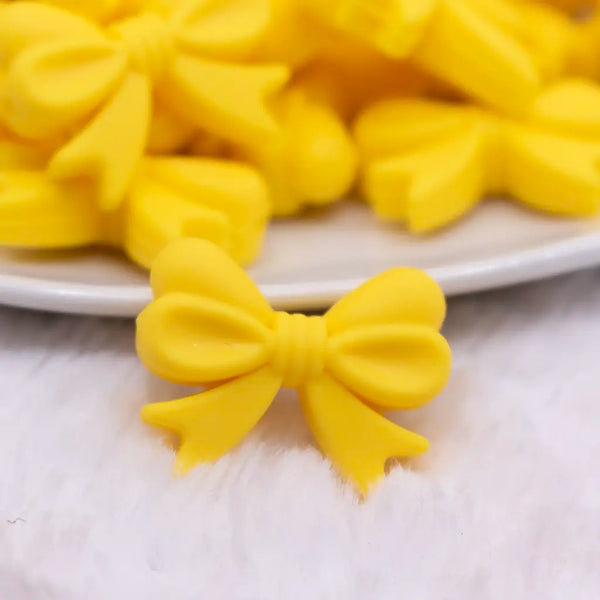 close up view of a pile of 25mm Yellow Bow Knot silicone bead