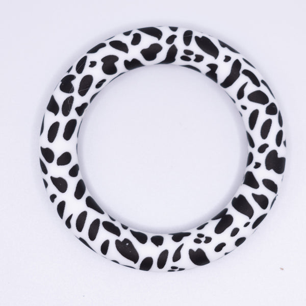top view of a pile of 65mm black cow print Design Round Ring Silicone Focal Beads Accessory