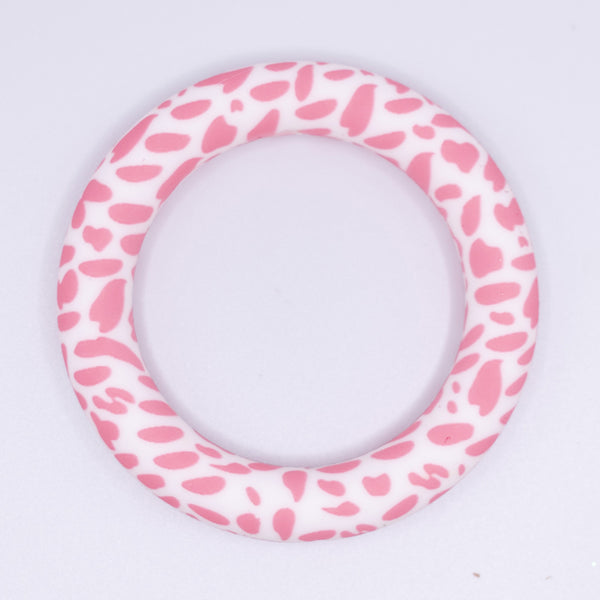 top view of a pile of 65mm pink cow print Design Round Ring Silicone Focal Beads Accessory
