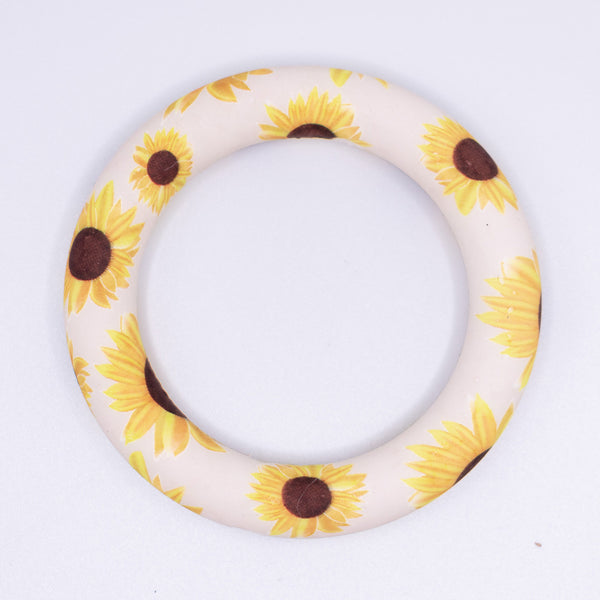 top view of a pile of 65mm Sunflower print Design Round Ring Silicone Focal Beads Accessory