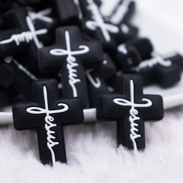 close up view of a pile of Black Cross with White writing Silicone Focal Bead Accessory