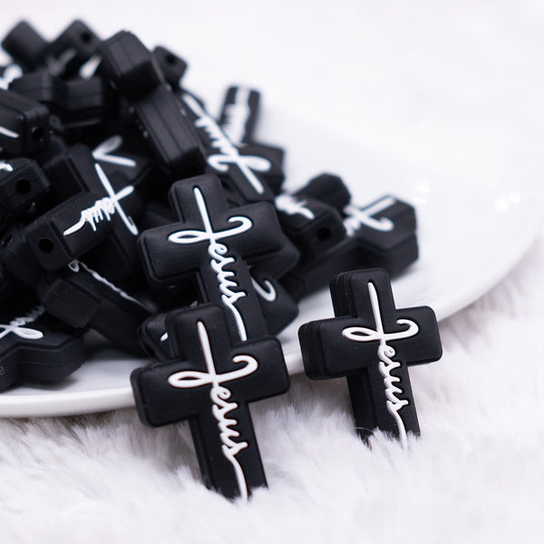 front view of a pile of Black Cross with White writing Silicone Focal Bead Accessory
