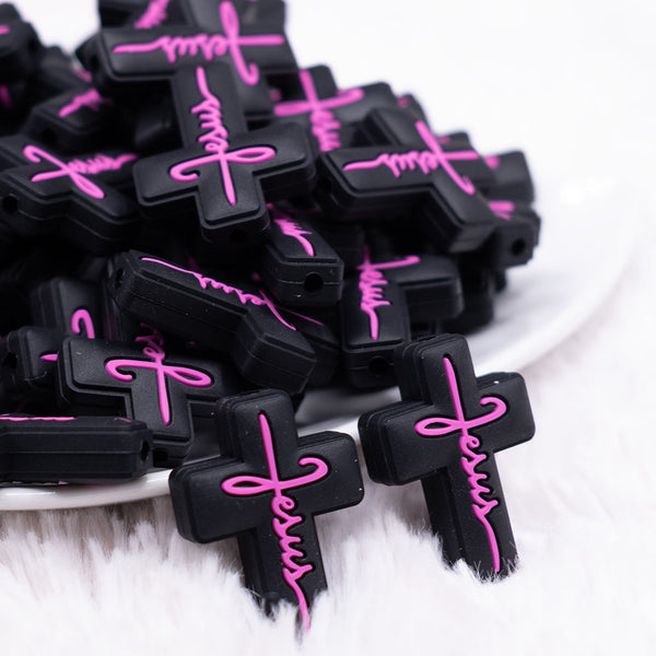 front view of a pile of Black Cross with Pink writing Silicone Focal Bead Accessory
