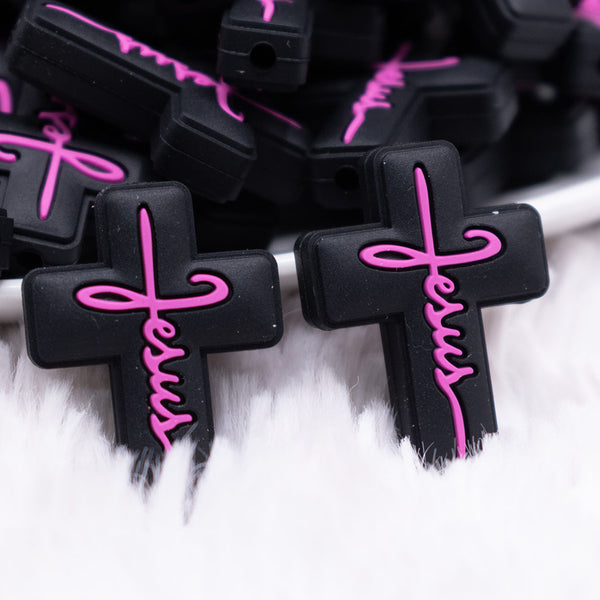 close up view of a pile of Black Cross with Pink writing Silicone Focal Bead Accessory