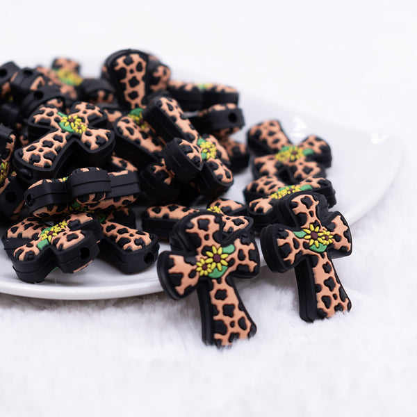 close up view of a pile of Cow Print Cross with Flower Silicone Focal Bead Accessory