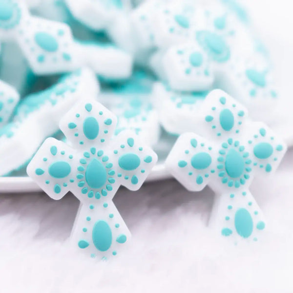 close up view of a pile of Cross with Teal print silicone focal bead