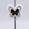close up front view of a pile of 23mm Black butterfly with rhinestone and pearl surround acrylic bead