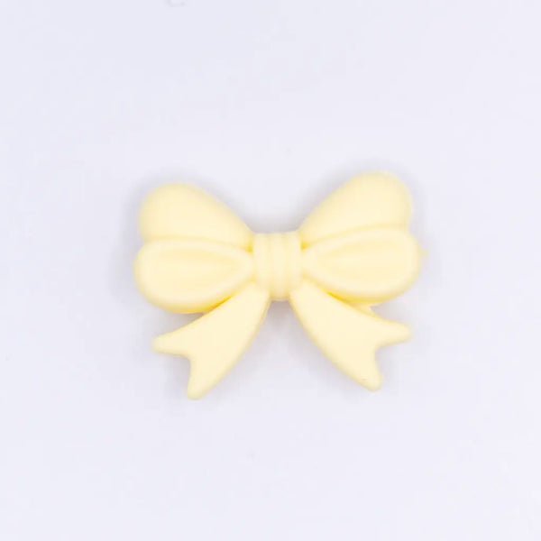 top view of a pile of 25mm Cream Yellow Bow Knot silicone bead