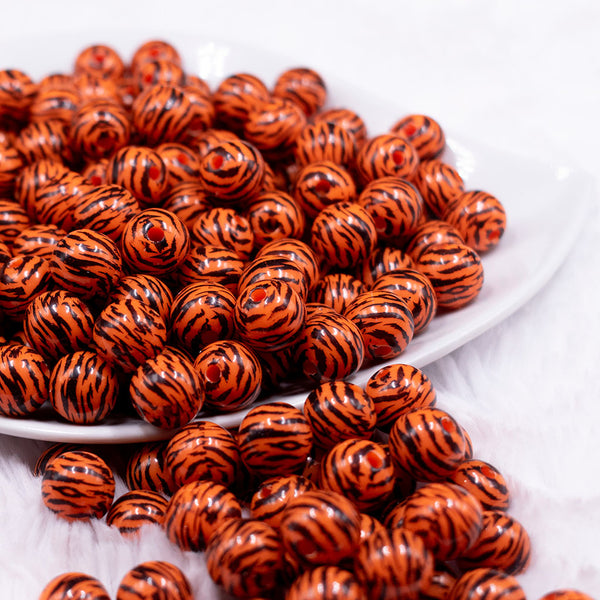 Front view of a pile of 12mm Orange & Black Tiger Print Chunky Acrylic Bubblegum Beads - 20 Count