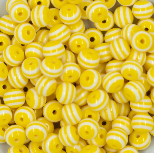 Close up view of a pile of 12mm Yellow with White Stripes Resin Chunky Bubblegum Beads