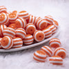 Front view of a pile of 16mm Orange with White Stripe Bubblegum Beads
