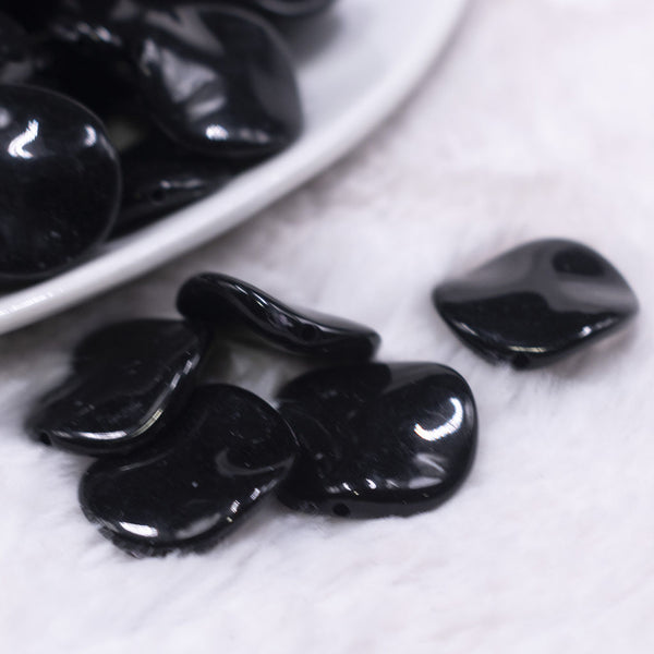 Macro view of a pile of 20mm Black Opaque Wavy Flat Shaped Jewelry Bead