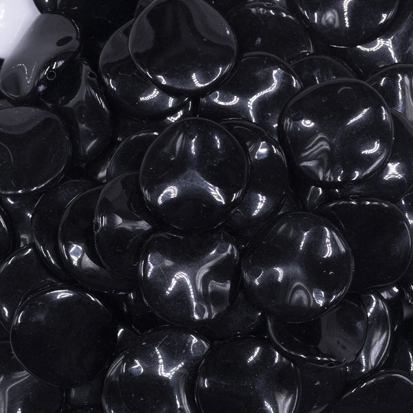 Close up view of a pile of 20mm Black Opaque Wavy Flat Shaped Jewelry Bead