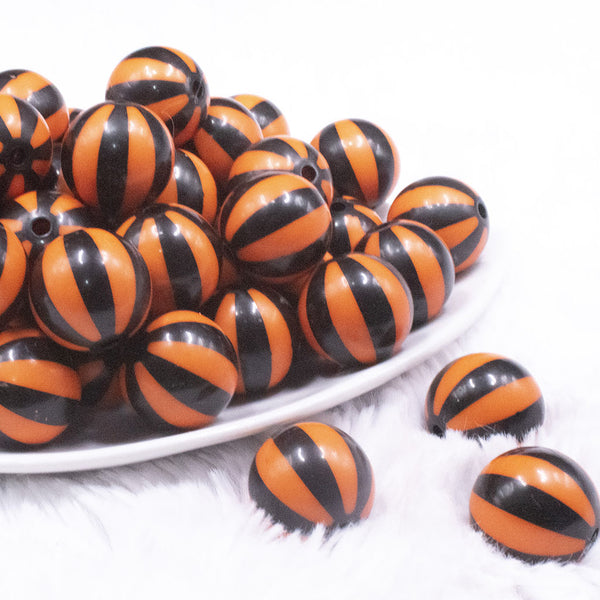 front view of a pile of 20mm Orange with Black Stripe Beach Ball Bubblegum Beads