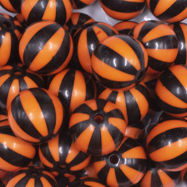 close up view of a pile of 20mm Orange with Black Stripe Beach Ball Bubblegum Beads