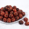 Front view of a pile of 20mm Orange with Black Splatter Chunky Acrylic Bubblegum Beads