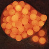Top view of a pile of glowing 20mm Orange Glow in the Dark Bubblegum Beads
