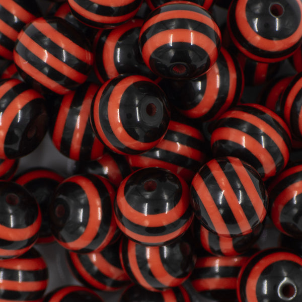 Close up view of a pile of 20mm Orange & Black Stripe Acrylic Chunky Bubblegum Beads