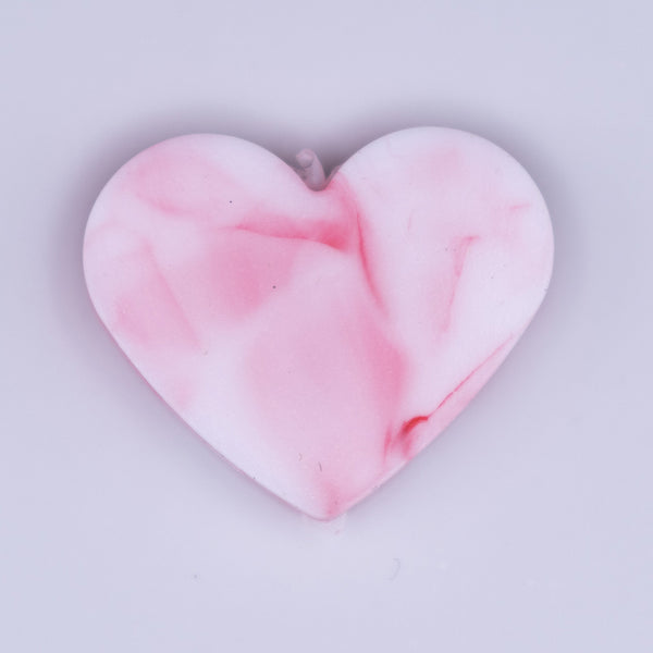 Close up view of a pile of 20mm Pink and White heart shaped silicone bead