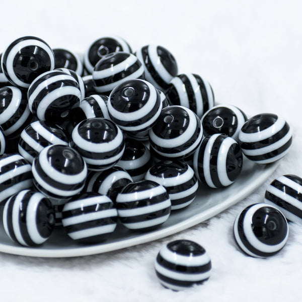 front view of a pile of 20mm Black with White Striped Chunky Bubblegum Beads in a white dish 