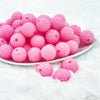front view of a pile of 20mm Bubblegum Pink beads featuring a rhinestone covered surface pictured on a white dish and white background