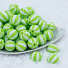 Front view of a pile of 20mm Lime Green with White Stripe Beach Ball Acrylic Chunky Bubblegum Beads