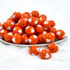 front view of a pile of 20mm Orange with White Hearts Bubblegum Beads