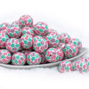 front view of a pile of 20mm Bubblegum white beads printed with pastel pink, green, and purple Flowers 