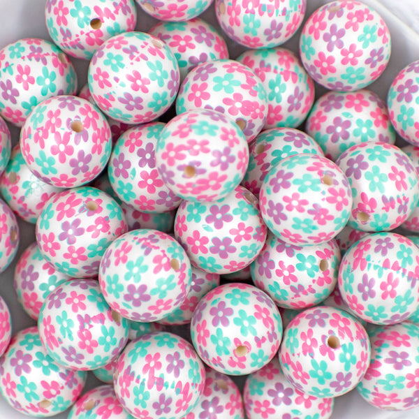 close up of a pile of 20mm Bubblegum white beads printed with pastel pink, green, and purple Flowers 