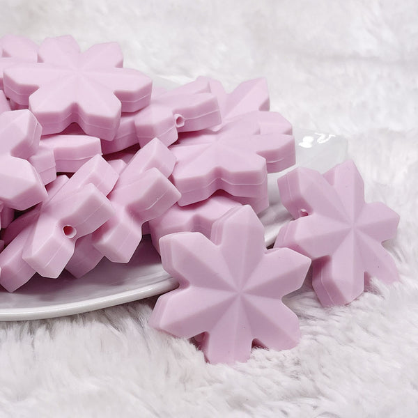 front view of a pile of Pink Snowflake Silicone Focal Bead Accessory - 40mm x 40mm