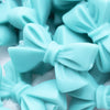 Close up view of a pile of 27mm Turquoise Blue Bow Knot silicone bead