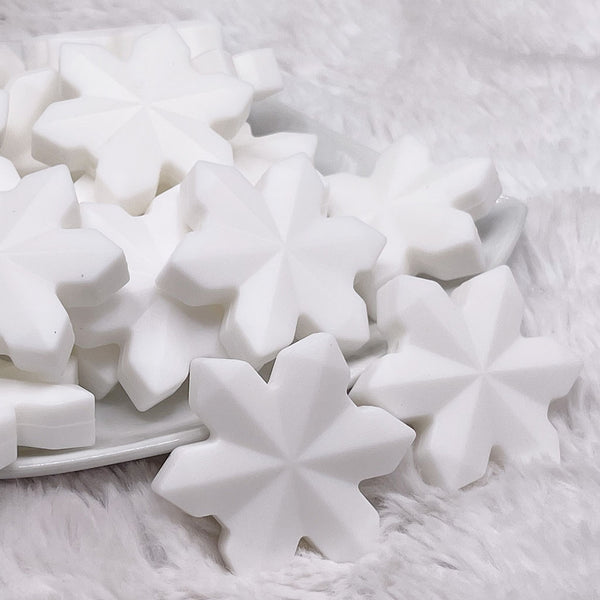 front view of a pile of White Snowflake Silicone Focal Bead Accessory - 40mm x 40mm