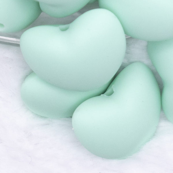 Close up view of a pile of 20mm Aqua Blue heart silicone bead