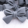Close up view of a pile of 27mm Dark Gray Bow Knot silicone bead