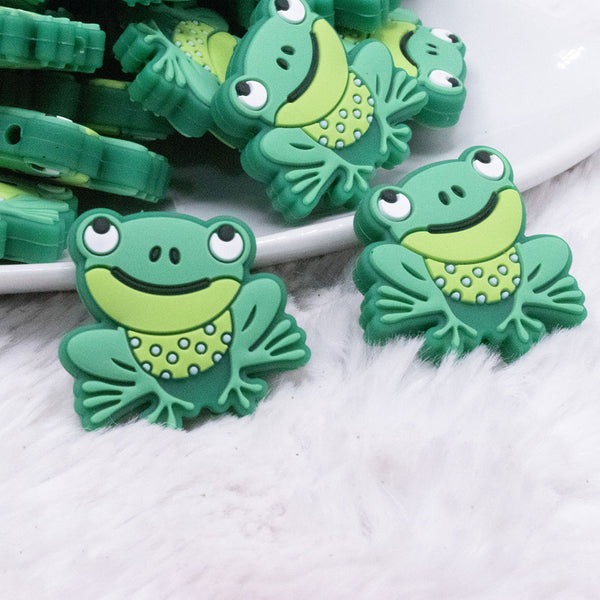 front view of a pile of Green Frog Silicone Focal Bead Accessory - 30mm x 33mm