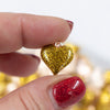Close up view of a pile of Gold Glitter Enamel Heart Charm 15mm