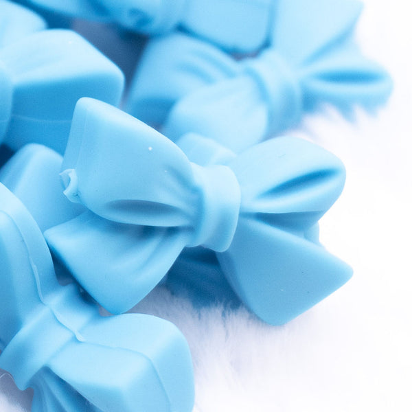 Close up view of a pile of 27mm Blue Butterfly Bow Knot silicone bead